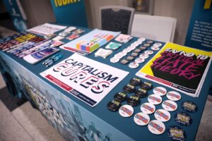 Table laid out with political posters that read "Capitalism Cures" and "Say No To Critical Hate Theory" and many political buttons